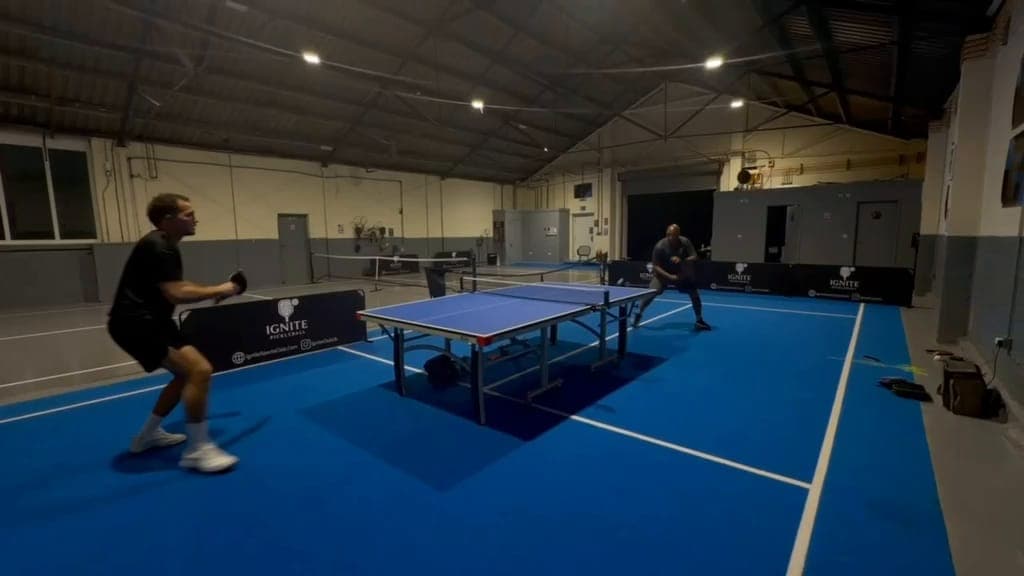The hall at Ignite at night, with a table tennis rally on the lit blue floor