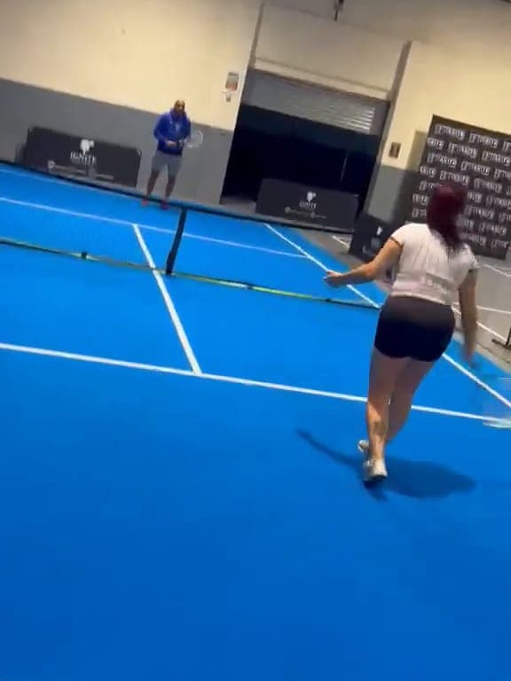 A player moves across the blue touch tennis court towards the net